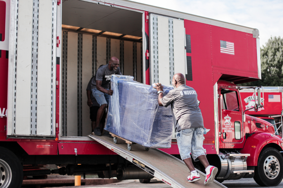 Two men moving furniture up ramp into moving truck